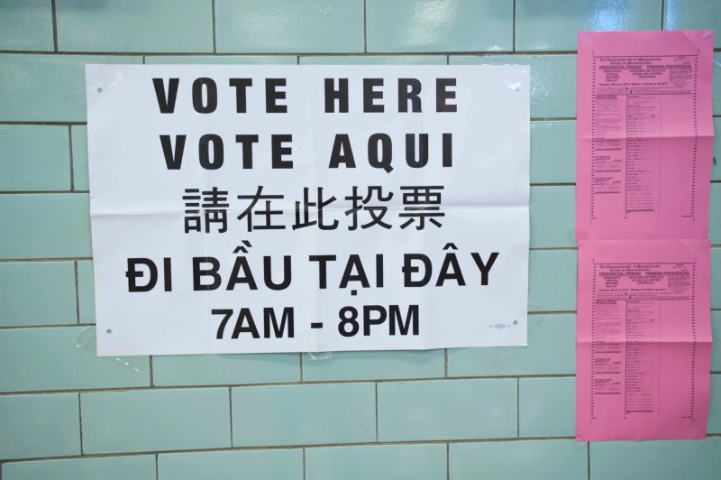 A voting sign on a wall in English, Spanish, and other languages.